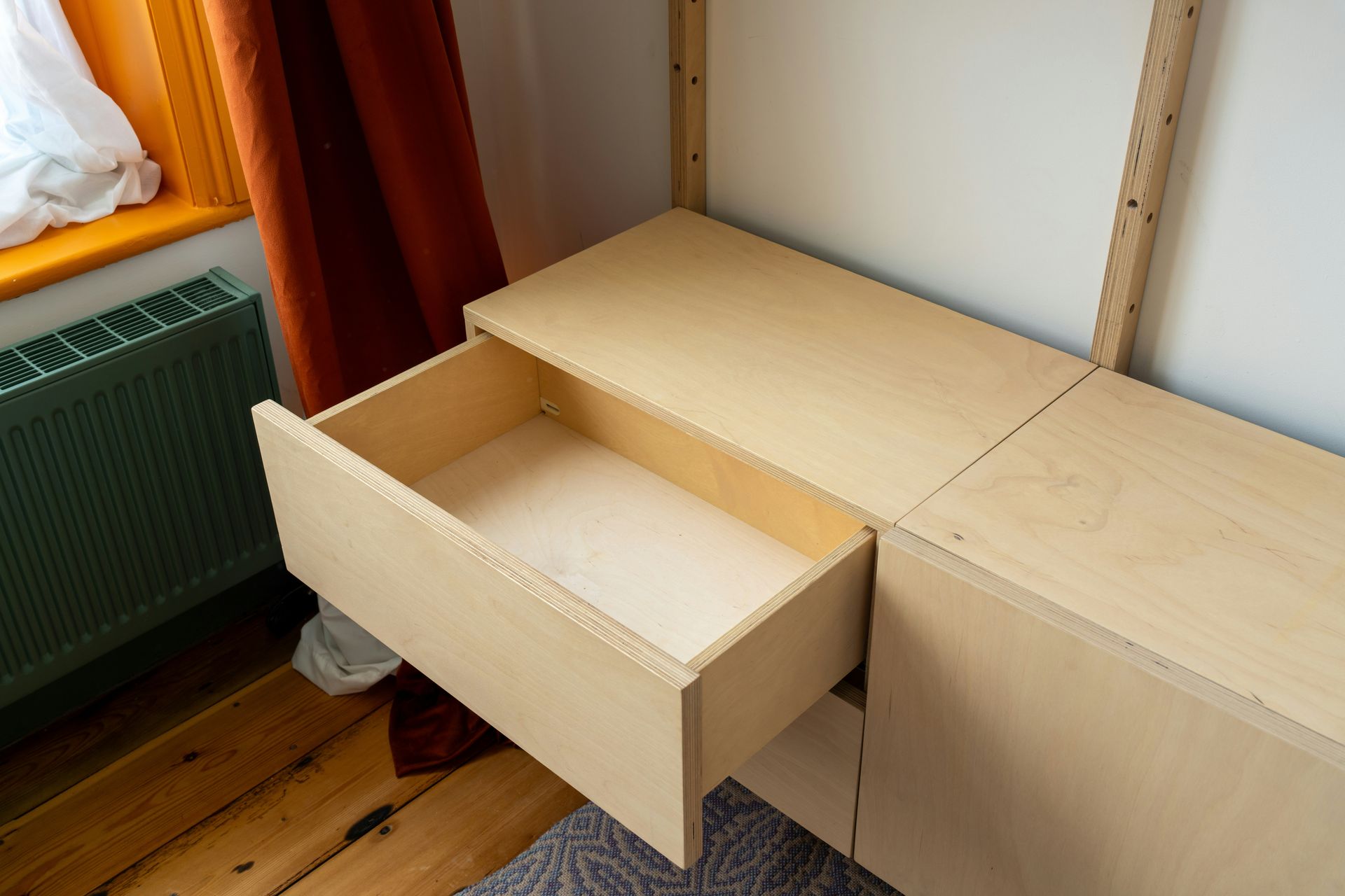 An open wooden drawer in a light wood cabinet.